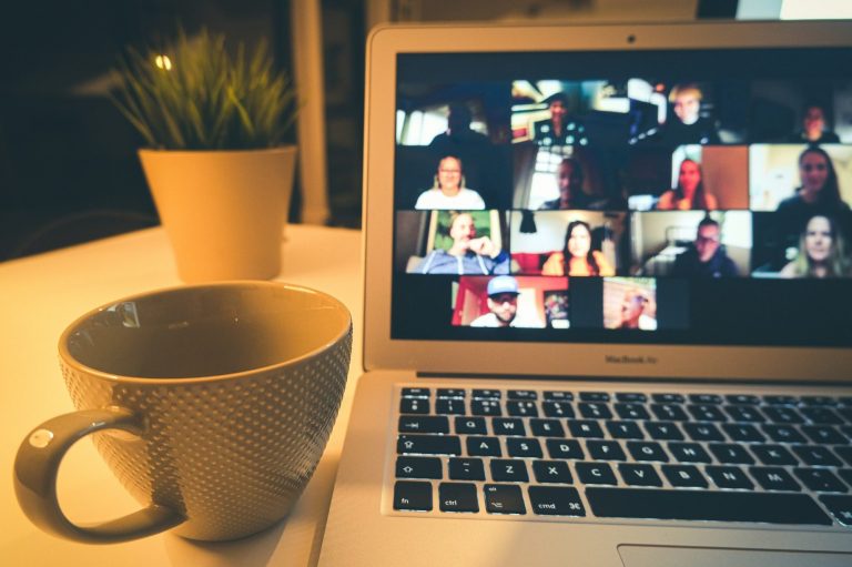 Ein Laptop mit geöffnetem Konferenz-Tool und eine Tasse daneben