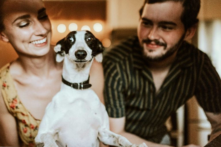 Ein Mann und eine Frau mit einem Hund auf dem Schoß, der die Augen aufreißt