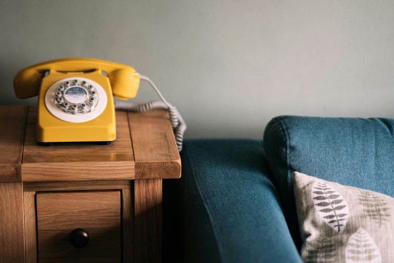 Gelbes Telefon neben blauer Couch
